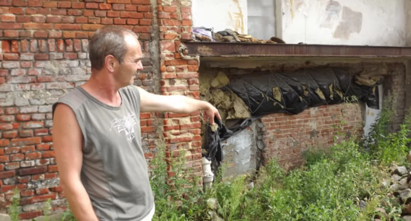 Marek Piechowiak wskazuje miejsce z drugiej strony budynku, przez które woda przelewa się do piwnic fot. Bartosz Woźniak