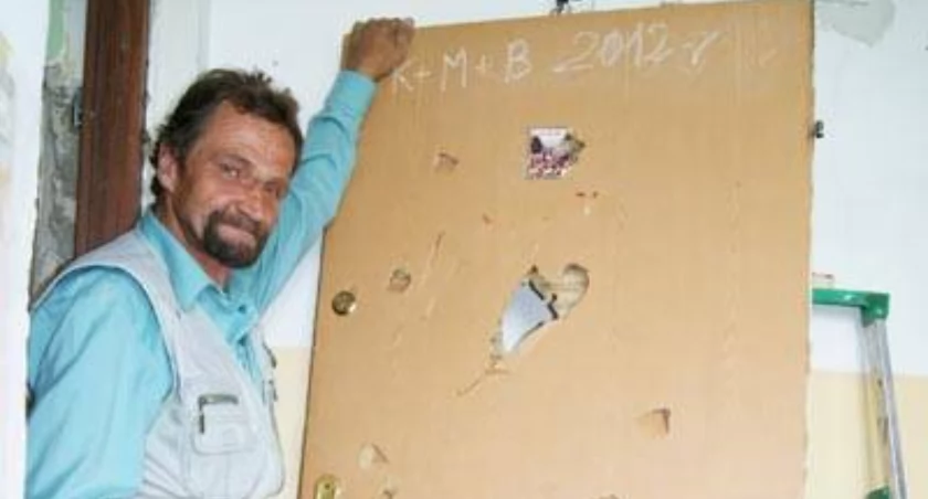 Alojzy Słodkiewicz pokazuje dziurę na wysokości wizjera, w którym dostrzegł ostrze siekiery i zdążył odskoczyć od drzwi fot. Arkadiusz Majszak