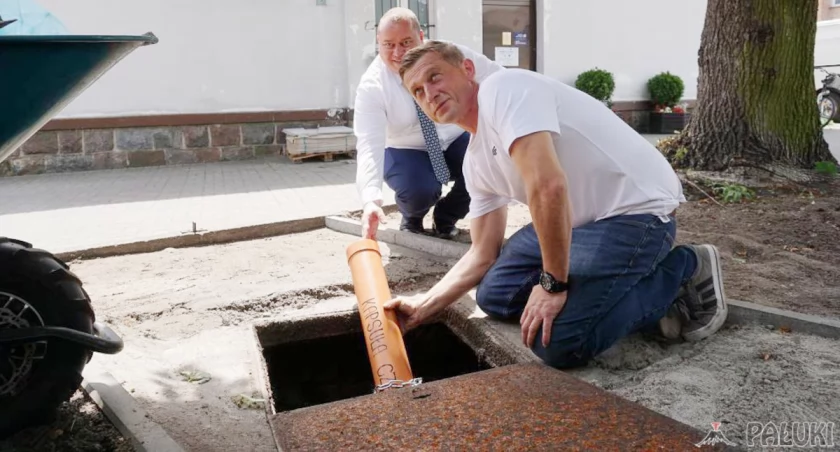 Mieszkaniec Janowca Wlkp. Michał Bystrzyński w asyście zastępcy burmistrza Michała Werkowskiego umieszcza kapsułę czasu w odkrytej studzience fot. Justyna Kulpińska