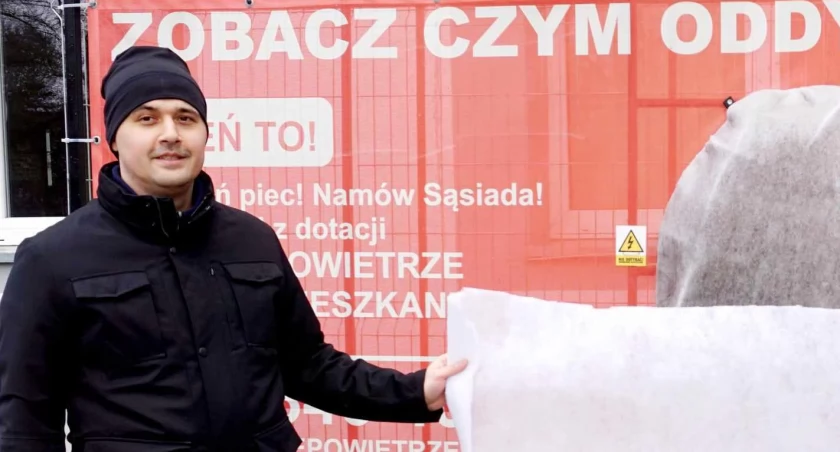 Maciej Rusnarczyk demonstruje czystą płachtę na tle łapacza smogu w Janowcu Wielkopolskim. Różnicę widać gołym okiem. fot. Justyna Kulpińska 