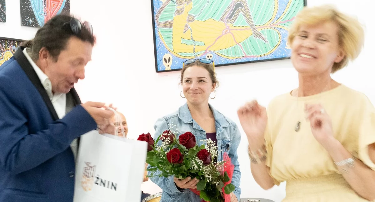Maciej Jeliński i jego żona Natalia (z kwiatami) otrzymują prezent od przedstawicieli władz Żnina