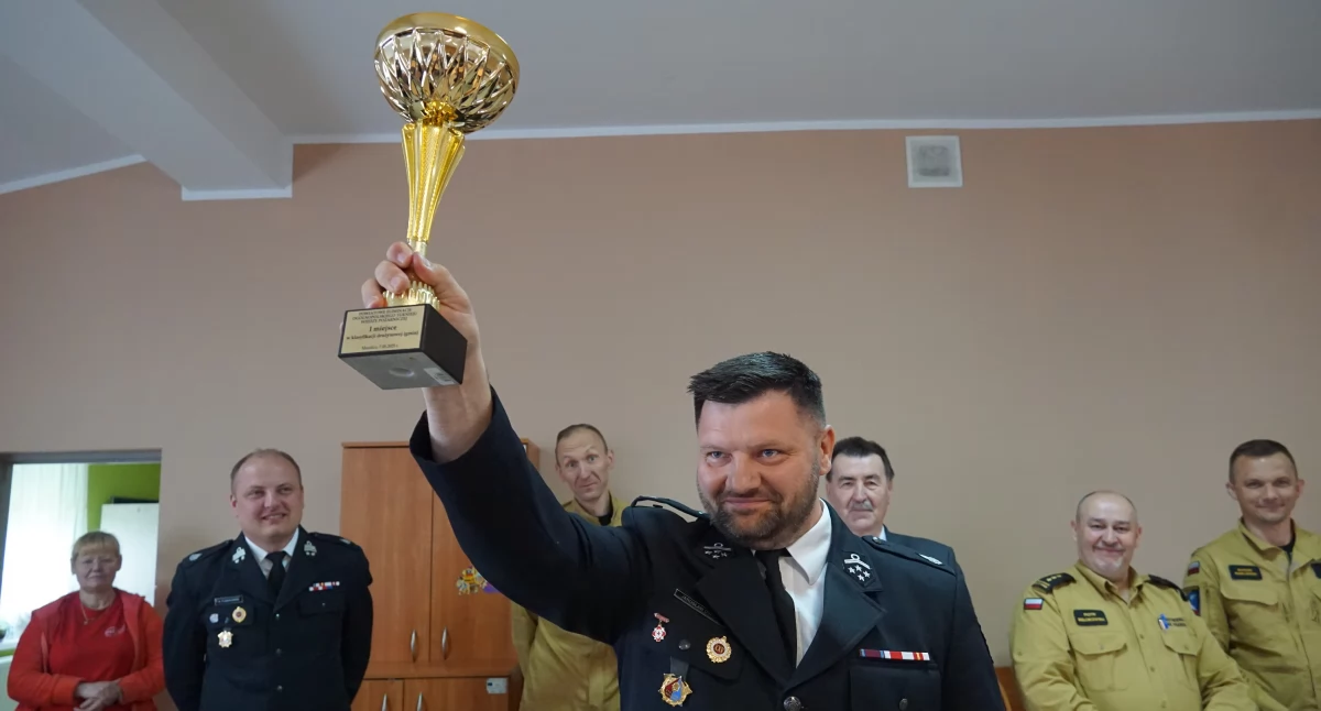 Jarosław Dypolt prezes Zarządu Miejsko-Gminnego ZOSP w Barcinie triumfalnie unosi puchar za zwycięstwo w klasyfikacji drużynowej fot. Karol Gapiński