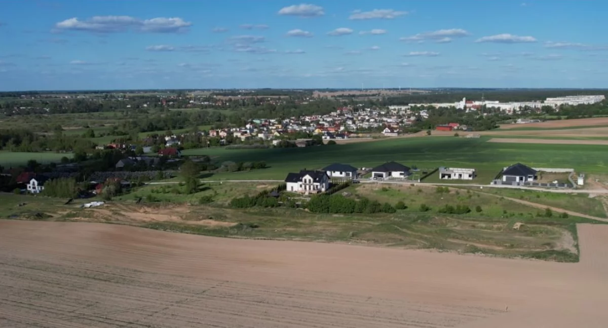 Widok z nieba nad Wolicami na osiedle domów jednorodzinnych, które wyrosło na dawnym polu Jakubisiaków. W dalszym tle widać kościół pw. św. Maksymiliana Marii Kolbego oraz bloki, które powstały na polach dawnego majątku Brzeskich w Krotoszynie. fot. Maciej Rejment