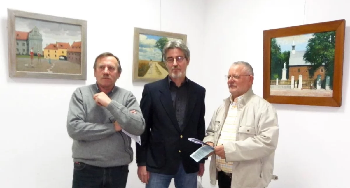 Marian Thiede (w środku) na wernisażu swych prac w Barcinie opowiadał o nich oglądającym, ale niewiele. Artysta wychodzi z założenia, że za niego mają mówić jego prace. To zaś, jak przemawiają do każdego widza, jest już z kolei wynikiem jego indywidualnej wrażliwości. Na zdjęciu w brązowej ramie widać też jeden z efektów bytności Mariana Thiede na plenerze malarskim na Pałukach podczas tegorocznego lata - obraz kościoła w Gąsawie. fot. Karol Gapiński